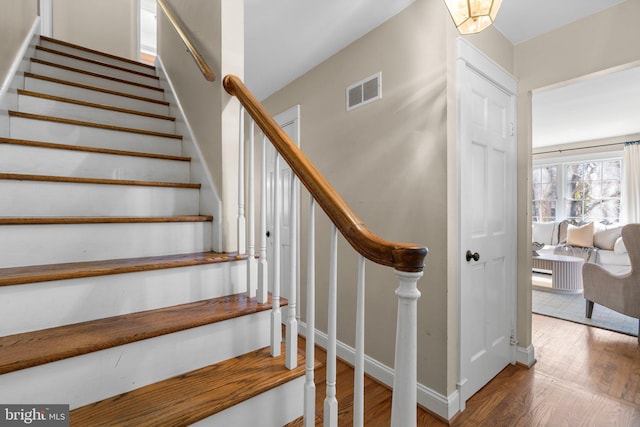 stairs with wood finished floors, visible vents, and baseboards