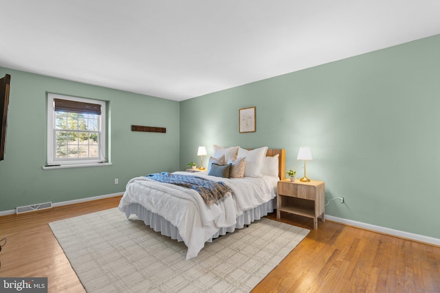 bedroom with visible vents, baseboards, and wood finished floors