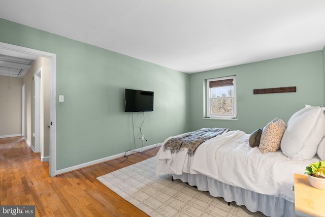 bedroom featuring attic access, baseboards, and wood finished floors