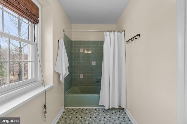 bathroom with a wealth of natural light, shower / tub combo, and baseboards