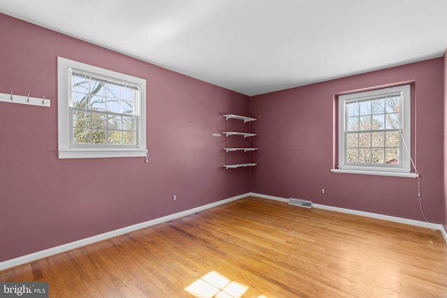 unfurnished room featuring light wood finished floors, visible vents, and baseboards