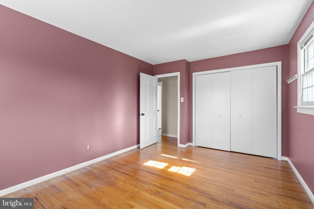 unfurnished bedroom featuring a closet, baseboards, and light wood finished floors