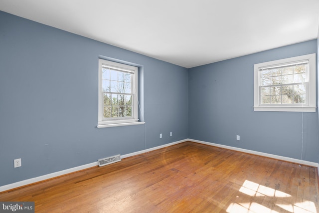 spare room featuring baseboards, visible vents, and wood-type flooring