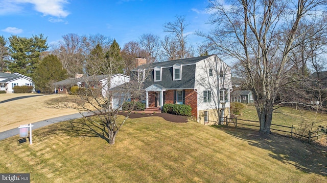 dutch colonial featuring a gambrel roof, a front lawn, driveway, fence, and brick siding