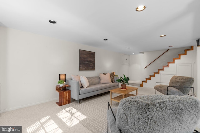 living area with recessed lighting, baseboards, light colored carpet, and stairs