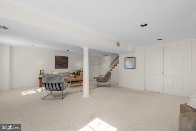 living area featuring ornate columns, visible vents, stairway, and carpet