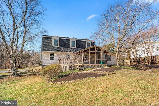 rear view of property with a lawn, fence, a sunroom, and roof with shingles