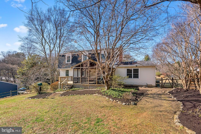 rear view of house with a wooden deck, a yard, and fence