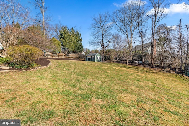 view of yard featuring a shed, an outdoor structure, and fence