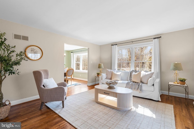 living area featuring wood finished floors, visible vents, and baseboards