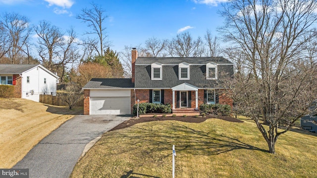 dutch colonial with driveway, an attached garage, a front yard, brick siding, and a chimney