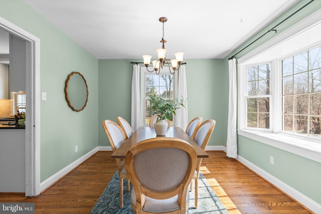 dining room featuring a notable chandelier, baseboards, and wood finished floors