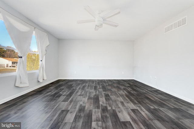 unfurnished room featuring dark wood finished floors, visible vents, and baseboards