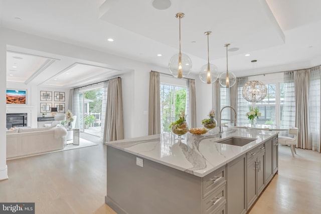 kitchen with light wood-type flooring, a glass covered fireplace, a sink, and gray cabinetry