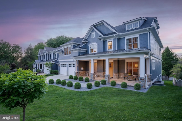 view of front facade featuring a garage, stone siding, a front lawn, and covered porch