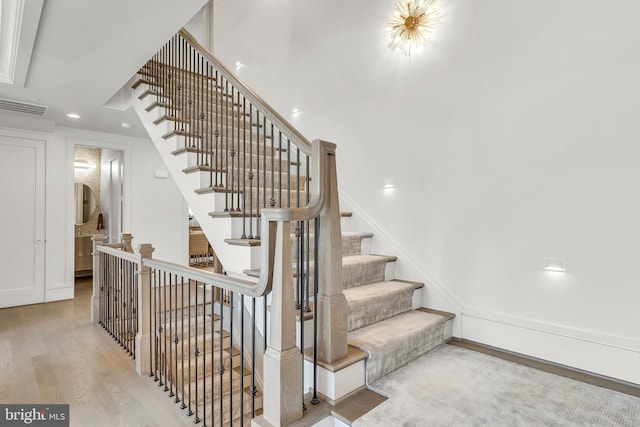 stairway with visible vents, wood finished floors, and recessed lighting