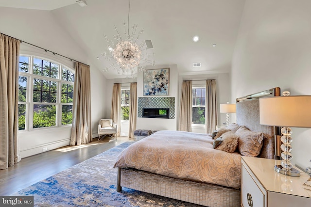 bedroom featuring visible vents, a chandelier, a tile fireplace, wood finished floors, and high vaulted ceiling