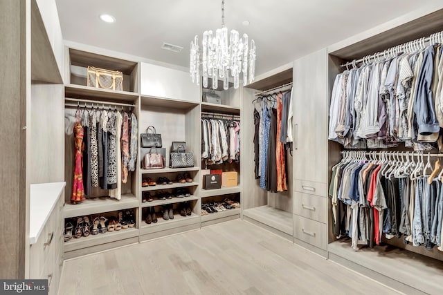 walk in closet featuring an inviting chandelier, visible vents, and wood finished floors