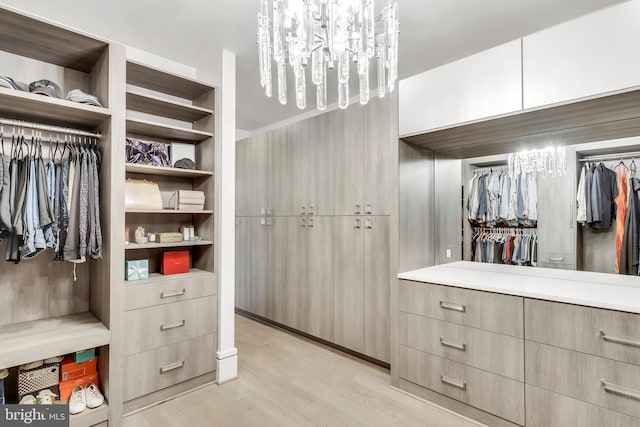 spacious closet featuring light wood finished floors and a notable chandelier