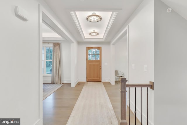 entrance foyer with baseboards, a raised ceiling, and light wood-style floors