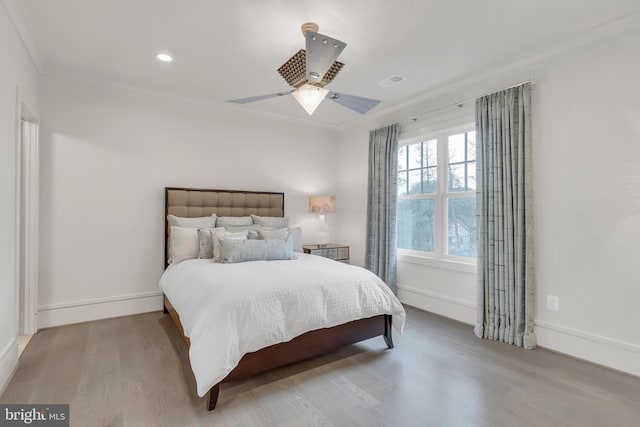 bedroom featuring a ceiling fan, baseboards, visible vents, and wood finished floors