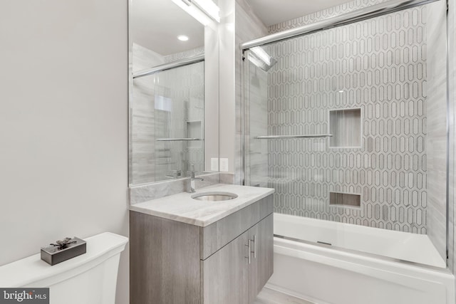 bathroom with vanity, toilet, and bath / shower combo with glass door