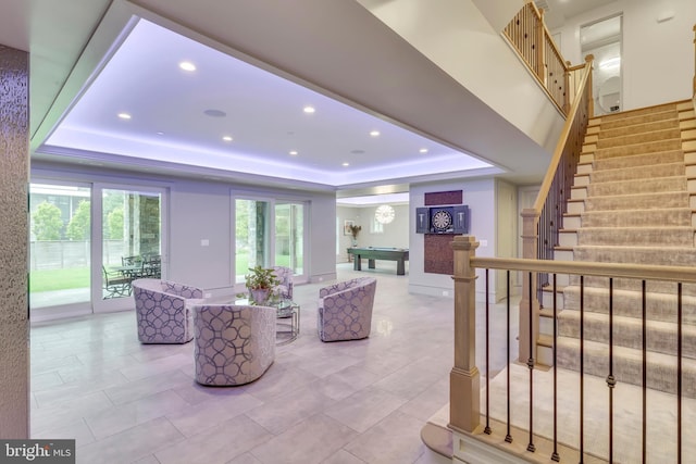 living room featuring a tray ceiling, pool table, recessed lighting, and stairs