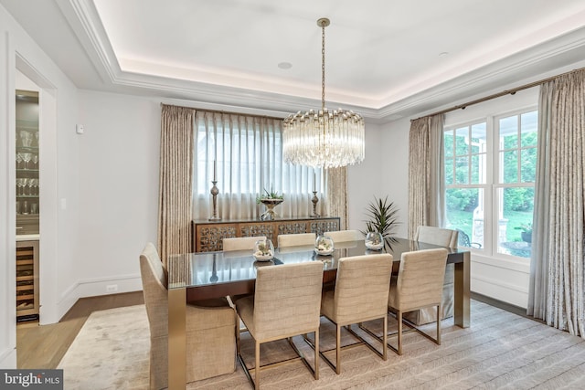 dining space with a raised ceiling, beverage cooler, baseboards, and an inviting chandelier