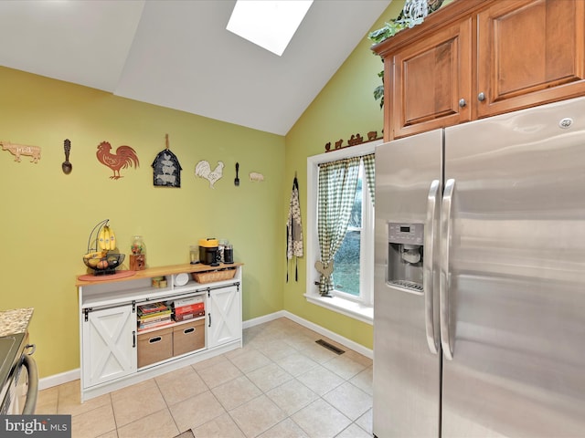 kitchen featuring light tile patterned floors, visible vents, lofted ceiling with skylight, light countertops, and stainless steel refrigerator with ice dispenser