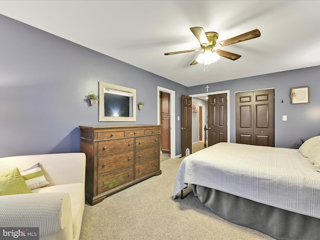 bedroom with multiple closets, light colored carpet, and ceiling fan