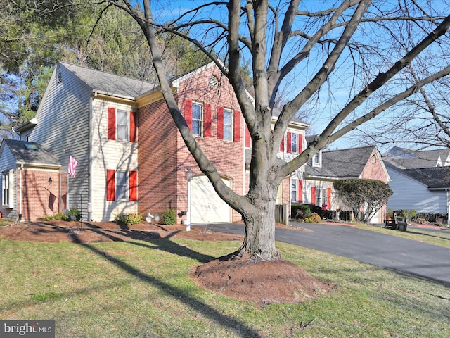 view of front of house with a garage, a front yard, brick siding, and driveway