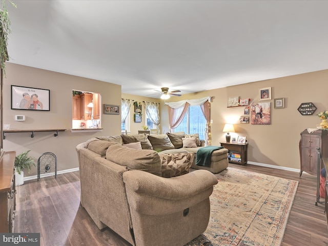 living room featuring dark wood-style floors, ceiling fan, and baseboards