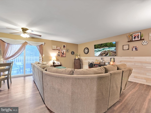 living area featuring a wainscoted wall, a ceiling fan, and wood finished floors