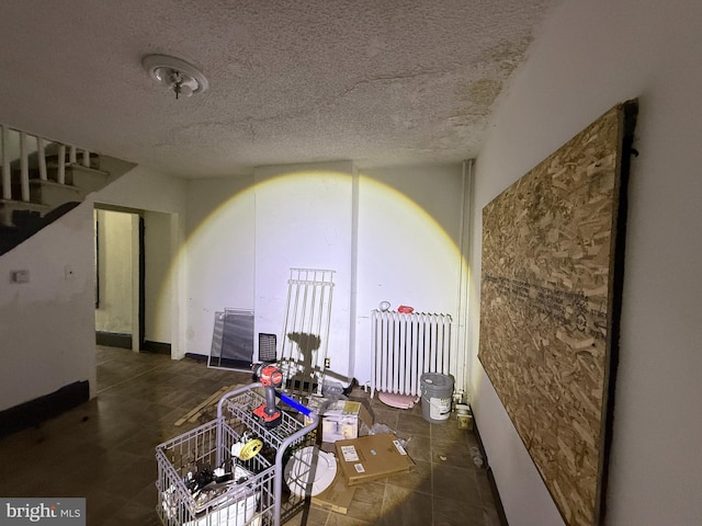 interior space with stairway, radiator heating unit, and a textured ceiling