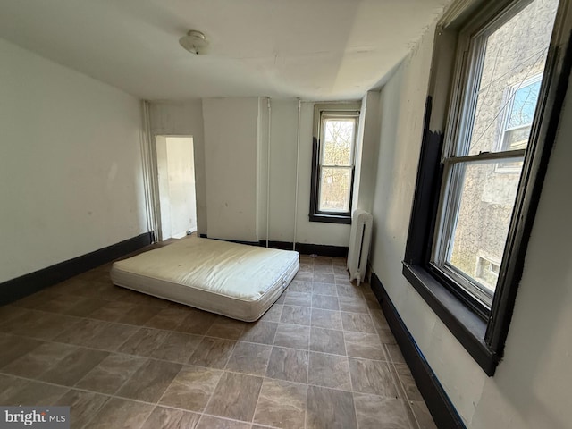 unfurnished bedroom with radiator and baseboards