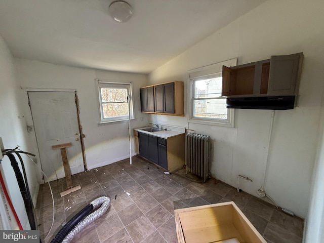 kitchen featuring under cabinet range hood, radiator, a healthy amount of sunlight, and light countertops