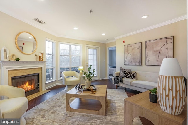 living area featuring visible vents, a lit fireplace, ornamental molding, recessed lighting, and wood finished floors