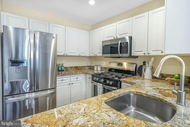 kitchen featuring a sink, light stone counters, white cabinetry, and stainless steel appliances