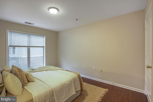 bedroom featuring dark wood finished floors, visible vents, and baseboards