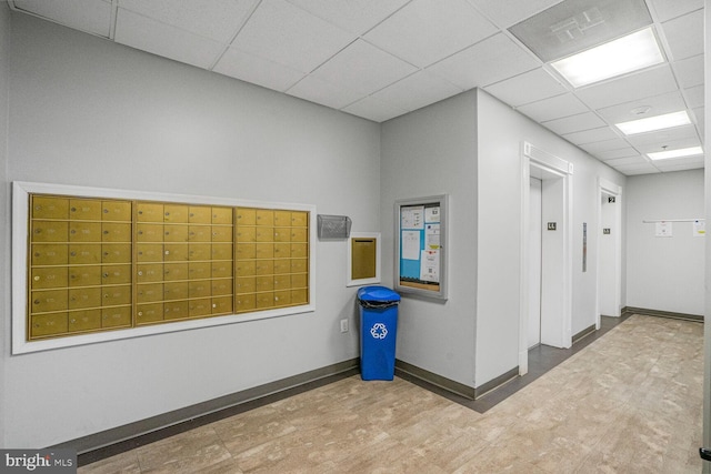 interior space featuring a paneled ceiling, mail area, elevator, and tile patterned floors