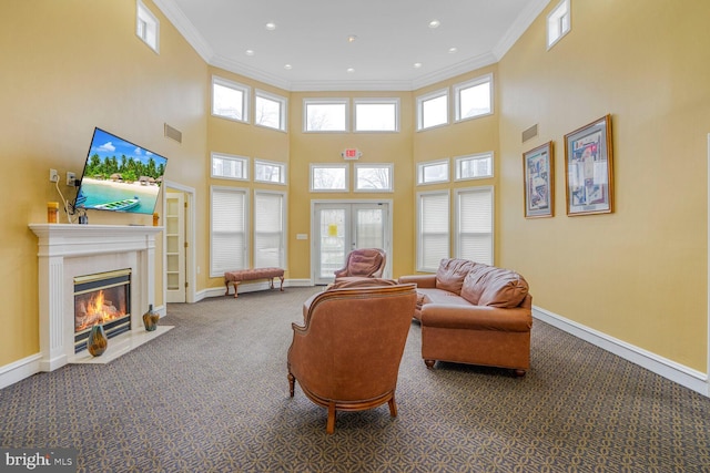 carpeted living room featuring a fireplace with flush hearth, visible vents, baseboards, and ornamental molding