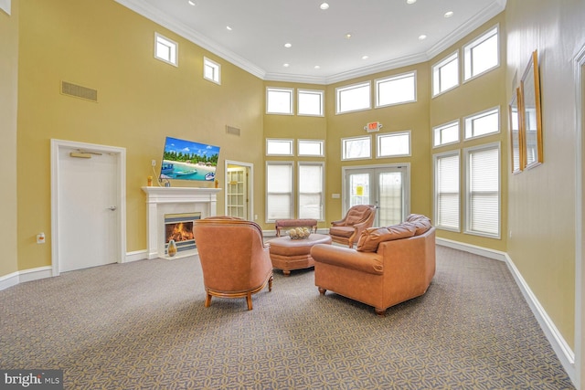 carpeted living room with visible vents, plenty of natural light, ornamental molding, and a fireplace