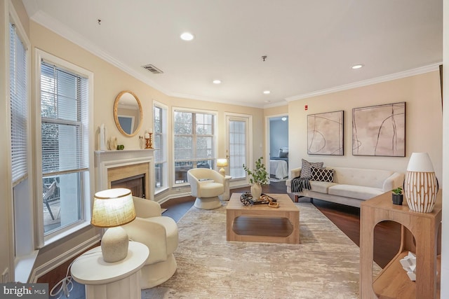 living room with a fireplace, crown molding, wood finished floors, and visible vents