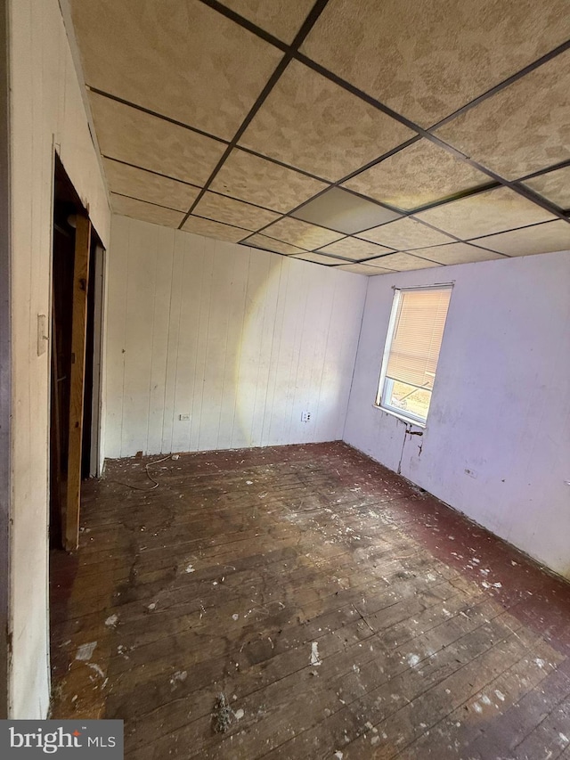 spare room featuring hardwood / wood-style floors, wooden walls, and a paneled ceiling