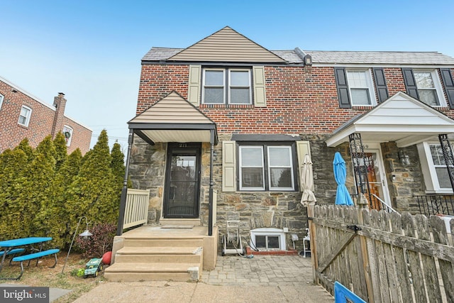 view of front of property with a fenced front yard, stone siding, and brick siding