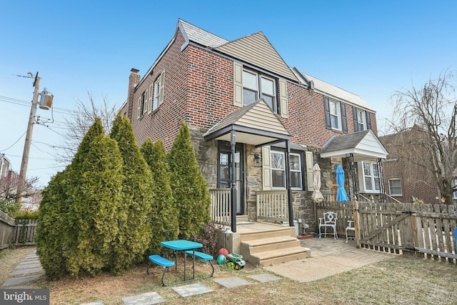 view of front of home with stone siding, brick siding, and fence