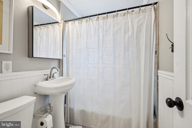 full bathroom featuring curtained shower, wainscoting, a sink, and toilet