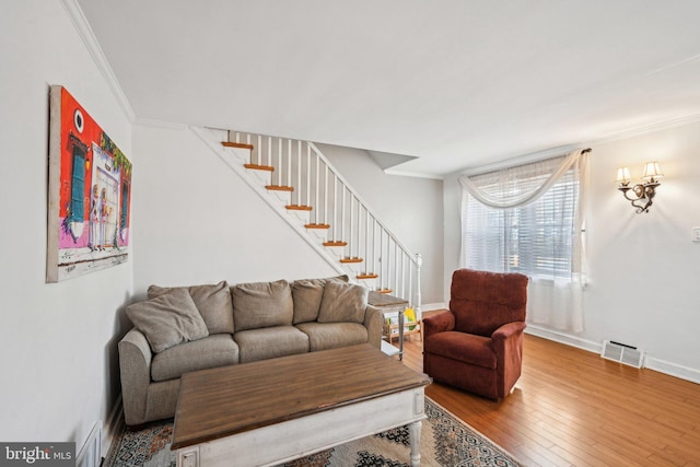 living room with visible vents, baseboards, stairs, ornamental molding, and wood-type flooring