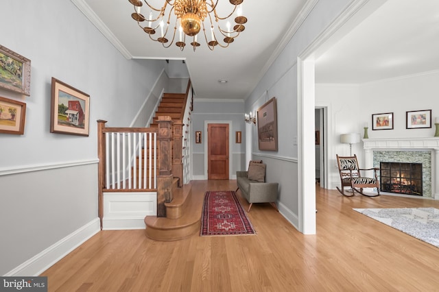 entryway with a premium fireplace, ornamental molding, stairs, and wood finished floors