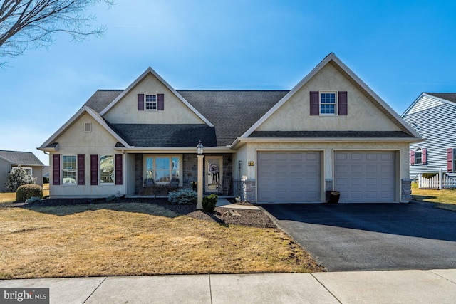 traditional-style home featuring aphalt driveway, a shingled roof, a front lawn, and stucco siding